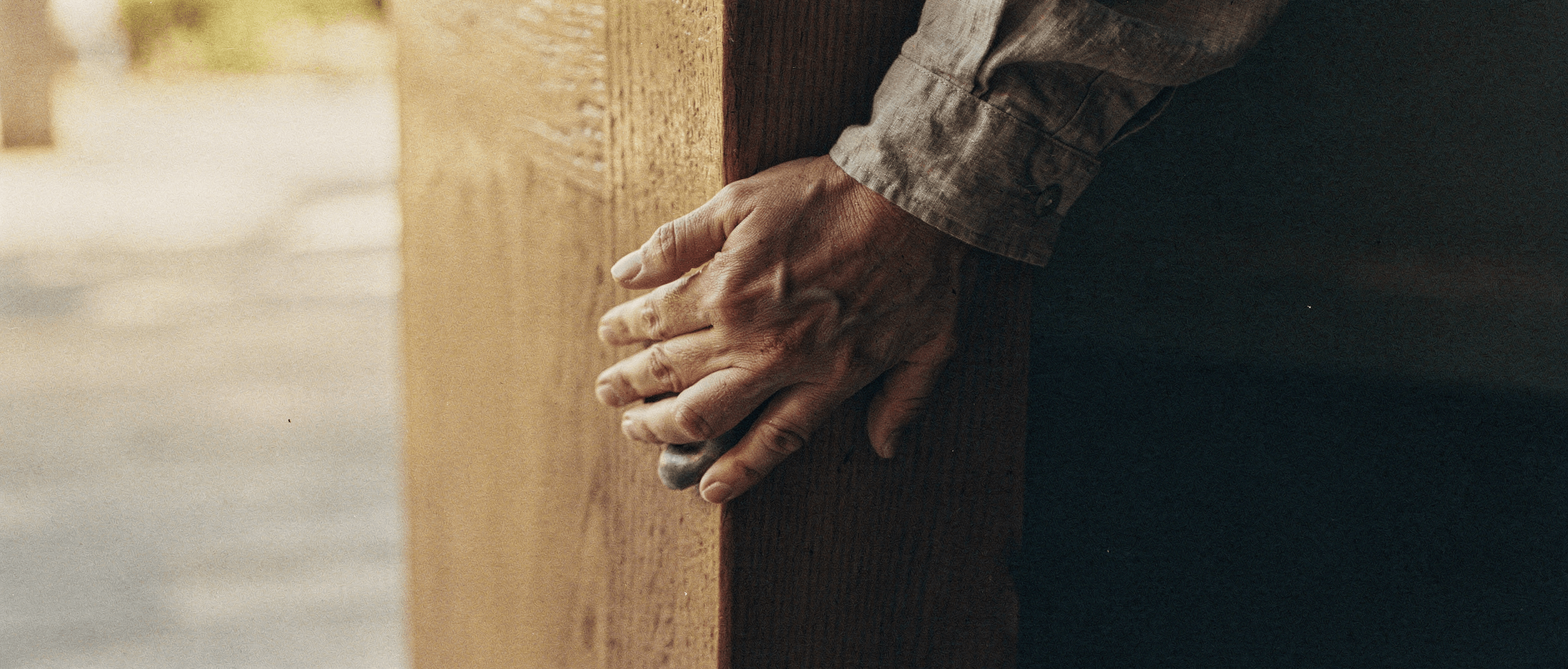 Two hands resting on a doorframe, warm interior light