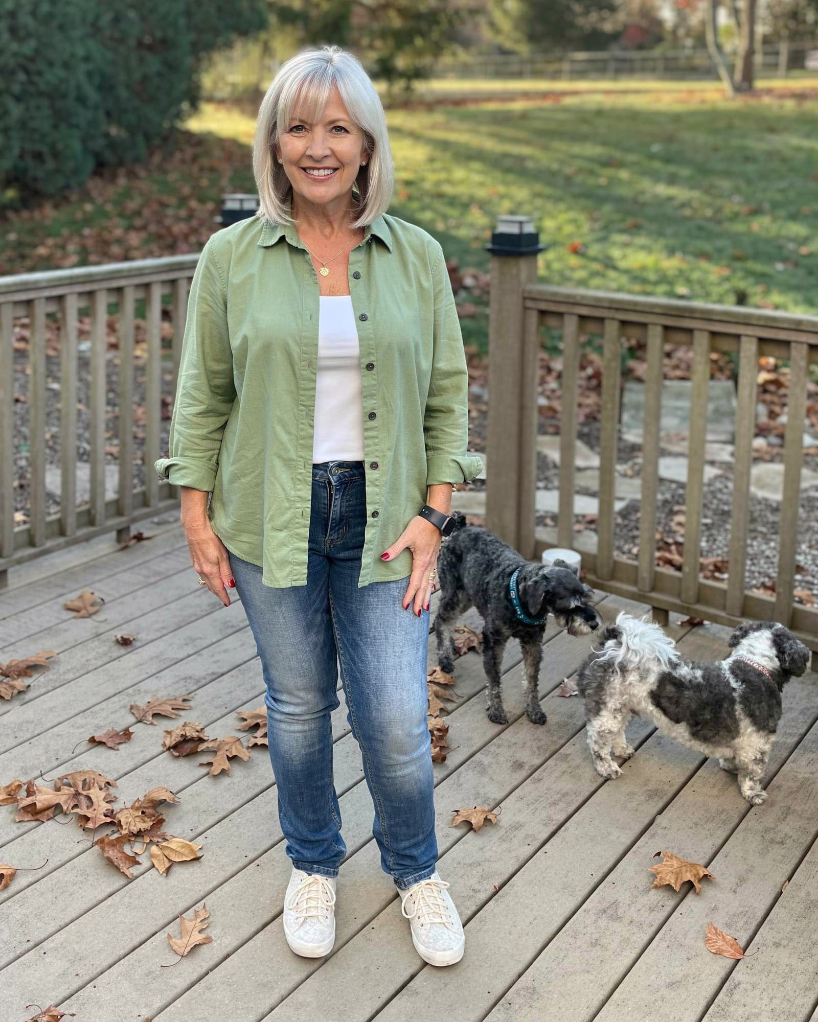 A content American woman in her mid fifties relaxing on her sunny back deck with her dogs, at ease.