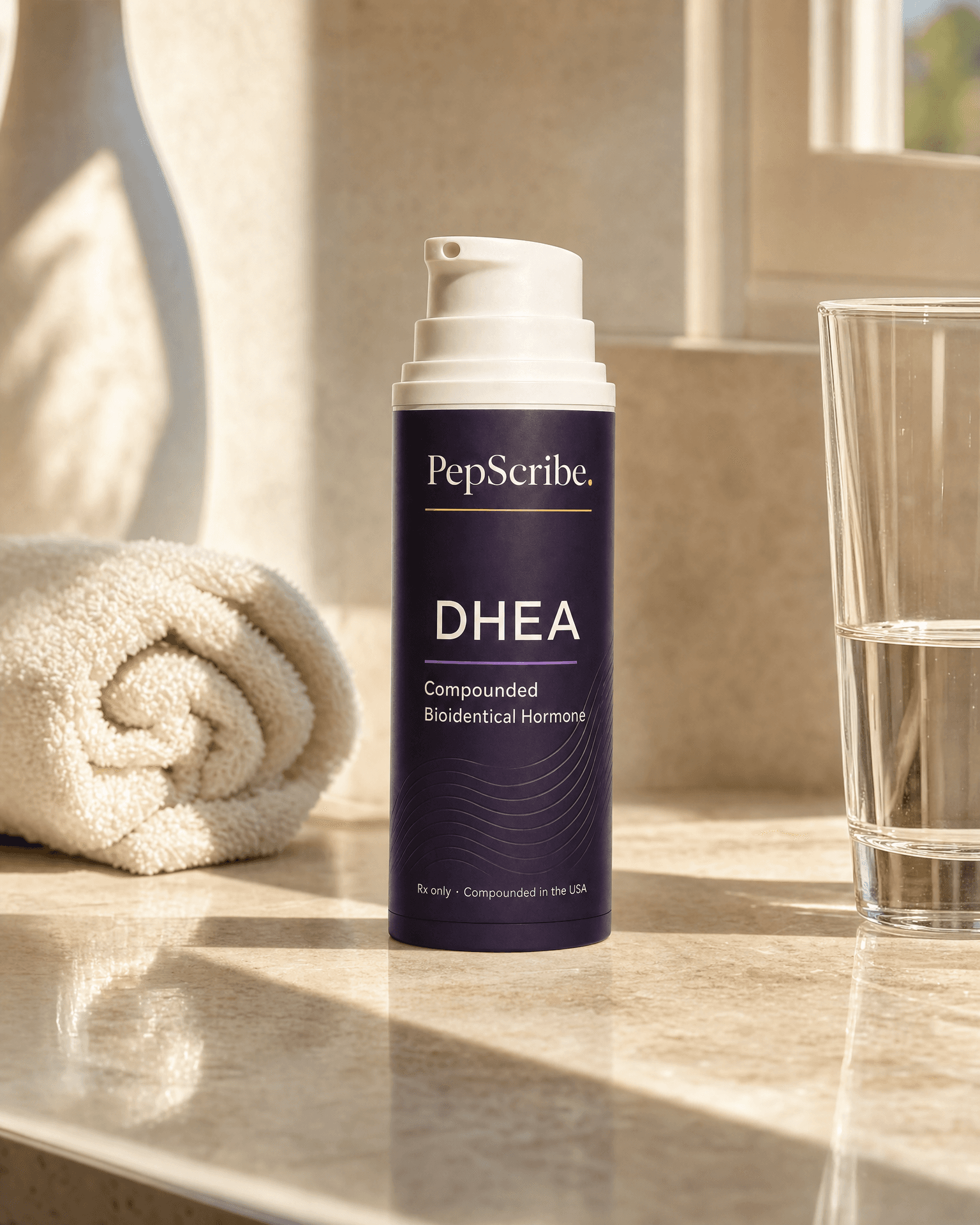 A PepScribe-branded compounded bioidentical DHEA cream bottle on a sunlit bathroom counter beside a rolled towel and a glass of water.