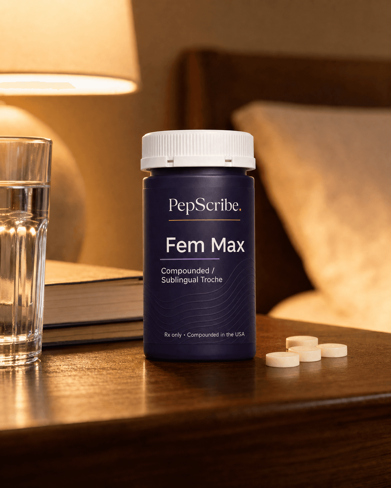 A PepScribe-branded Fem Max compounded sublingual troche bottle on a warm walnut nightstand beside a lamp, a book and a glass of water.