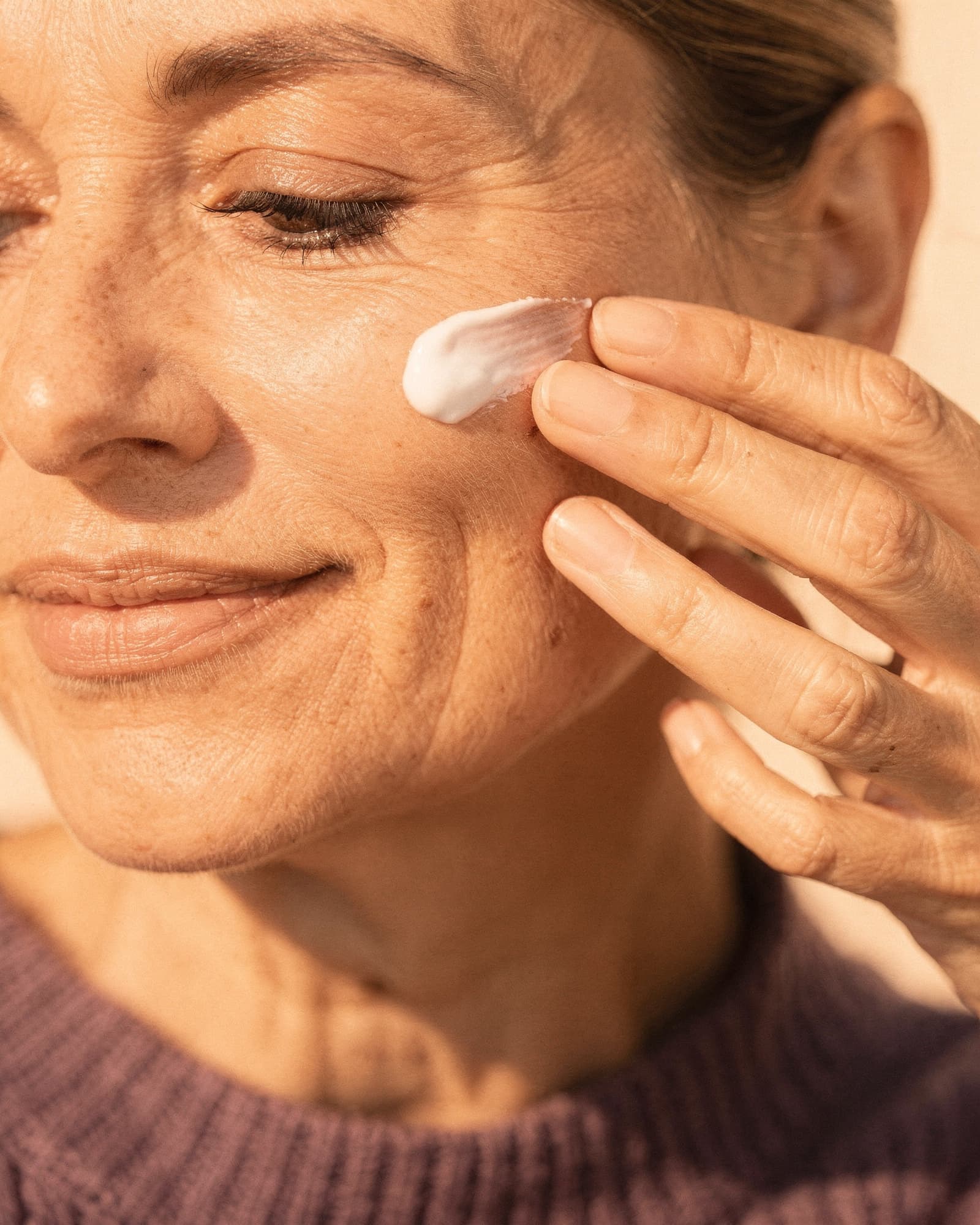 A close, candid frame of fingertips smoothing cream along the back of a hand