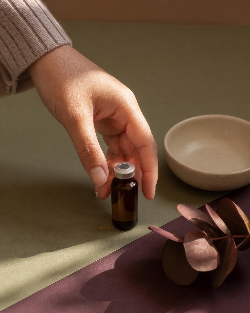 A hand lifting a small unlabeled amber compounded vial