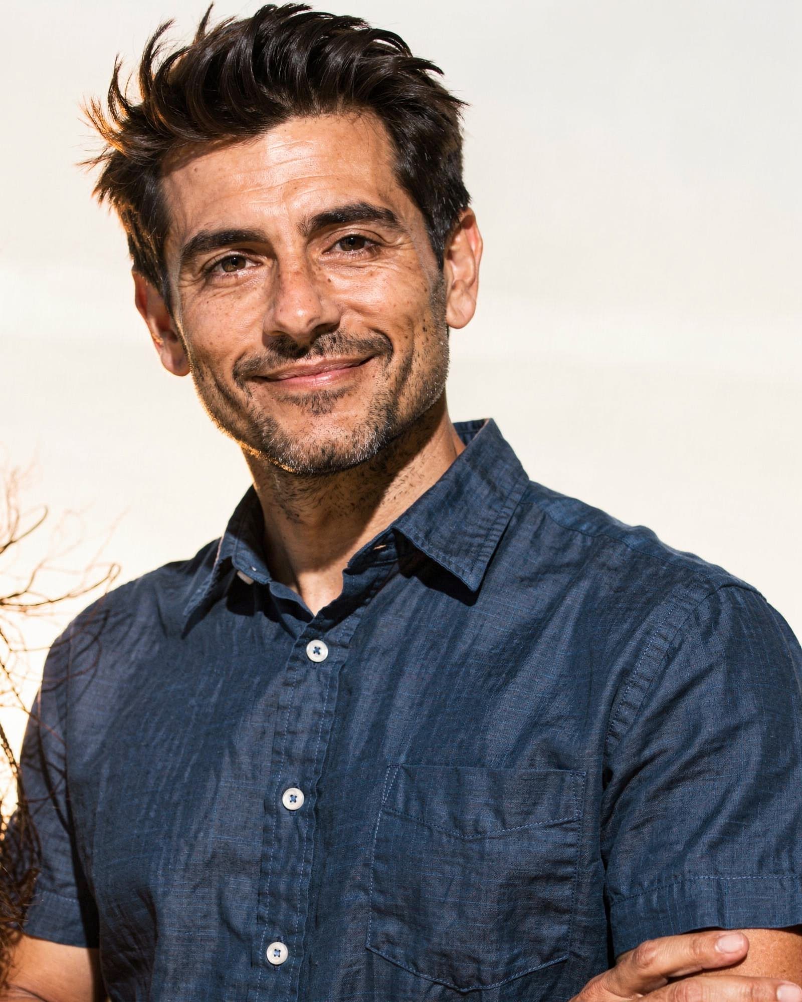 A warm, confident Latino American man in his early forties, relaxed and assured.