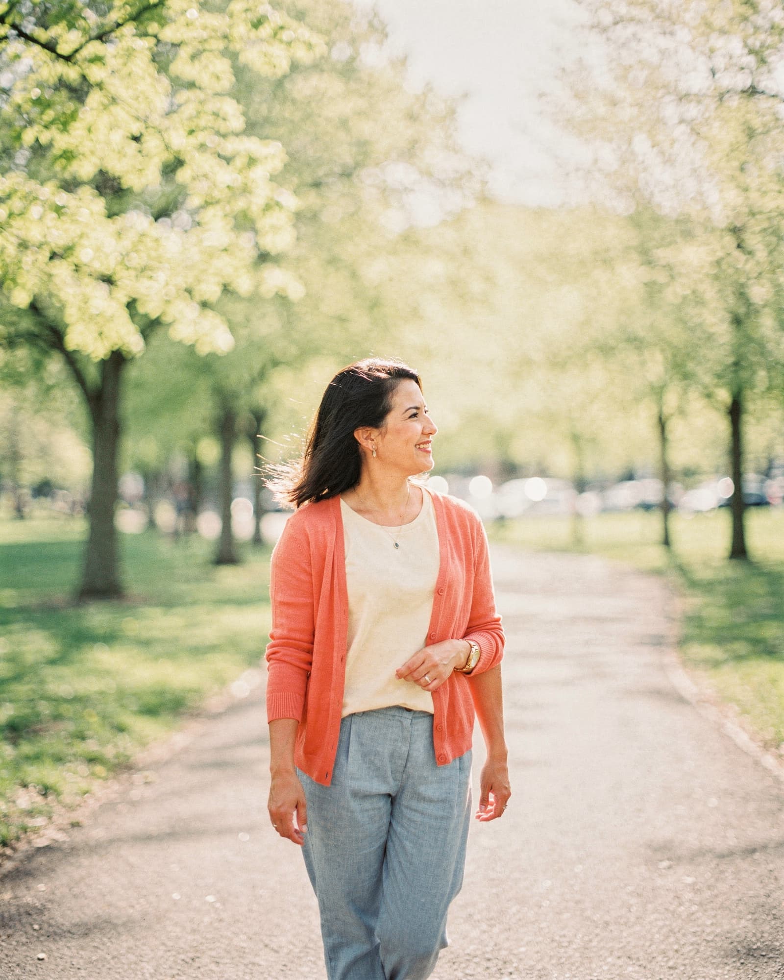Woman walking calmly on a sunlit park trail in late spring morning