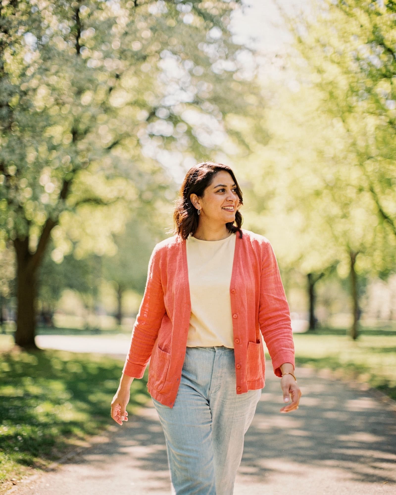 Woman walking on a sunlit park path in late spring morning