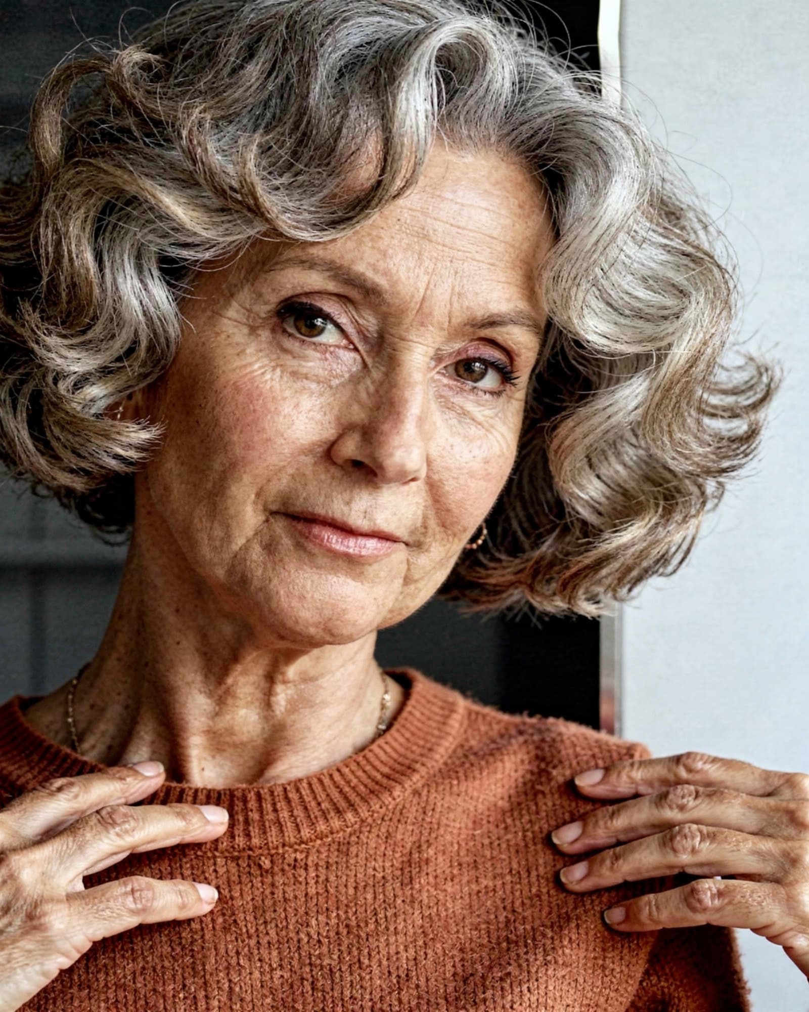 A warm, self-assured American woman in her mid fifties, calm and content, real age texture.