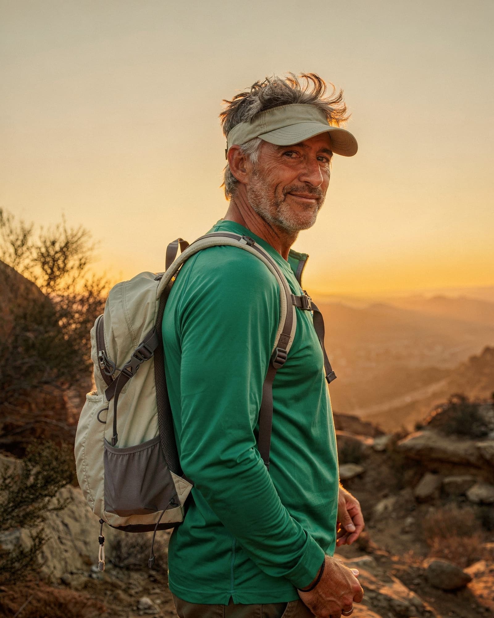 An active American man around fifty on an evening hike wearing a cap and light pack, calm and vital.