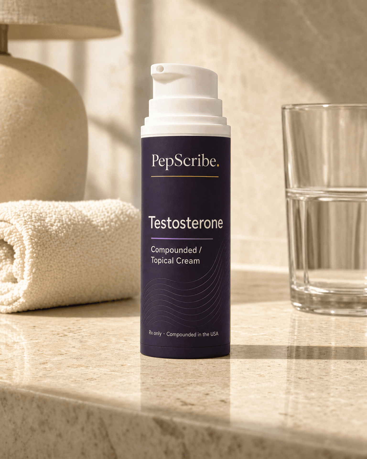 A PepScribe-branded compounded testosterone topical cream bottle on a sunlit bathroom counter beside a rolled towel and a glass of water.