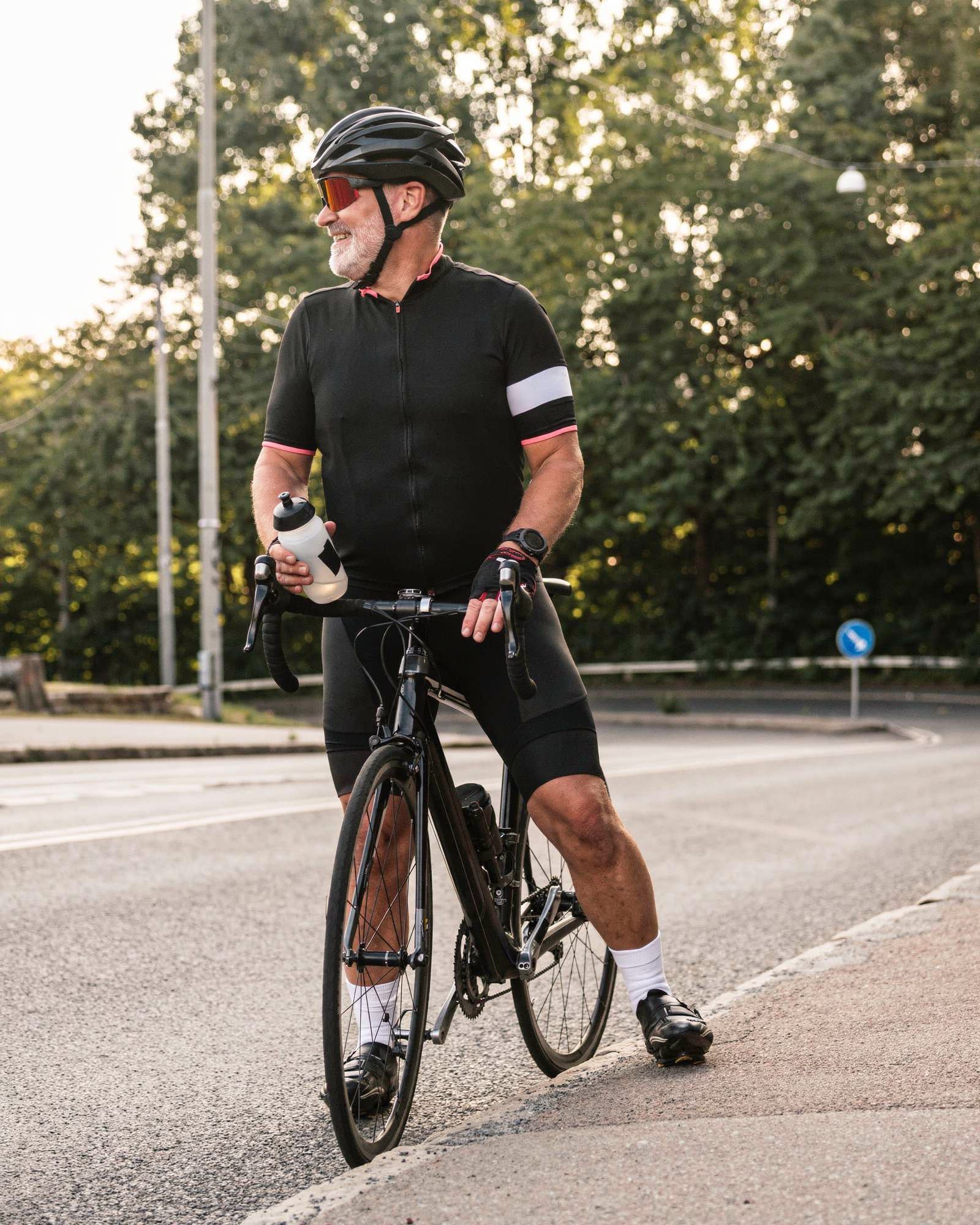 An active silver-bearded man in his late fifties pausing on his road bike during an evening ride.
